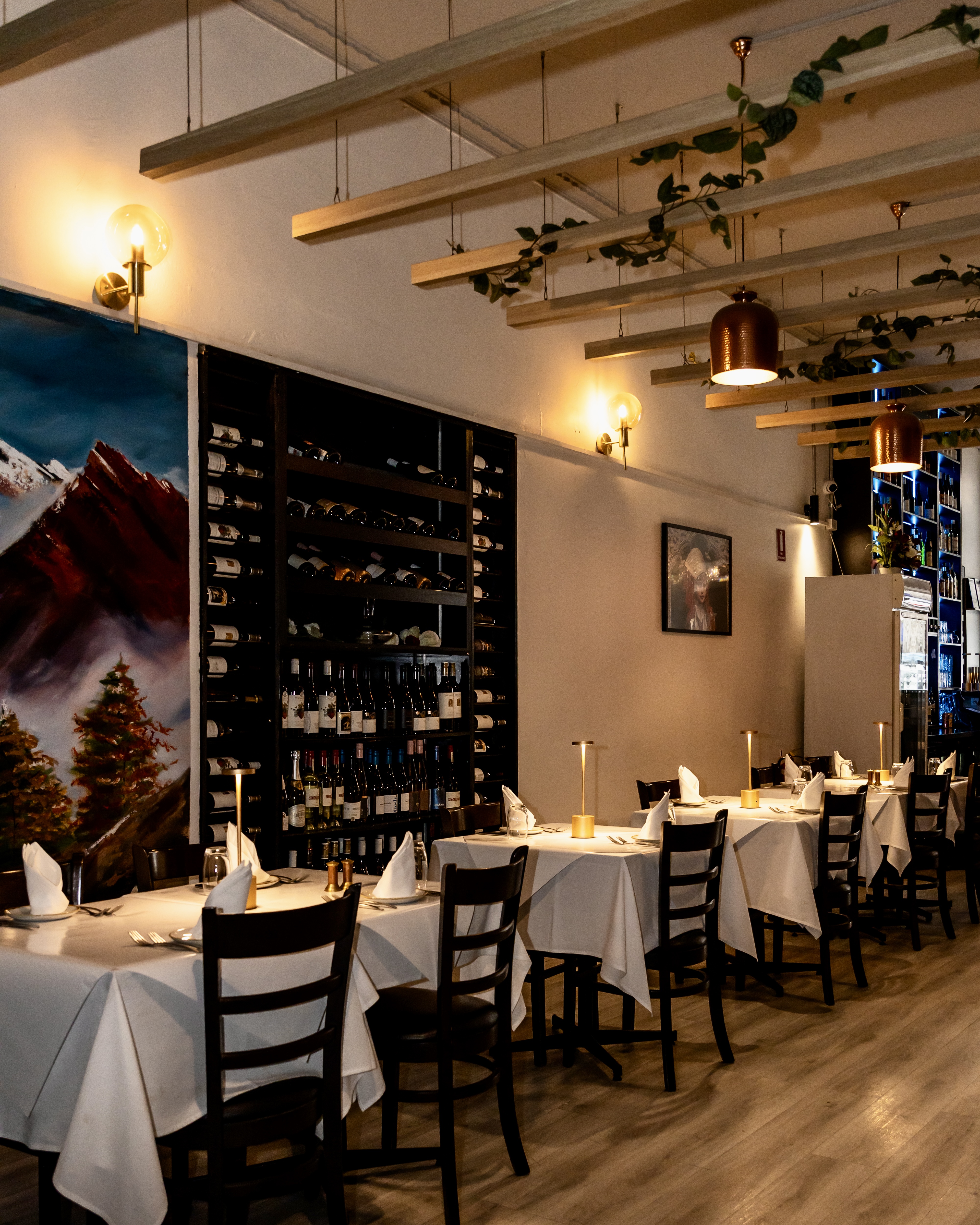 Aagaman Port Melbourne — warm dining room with wine wall and mountain mural